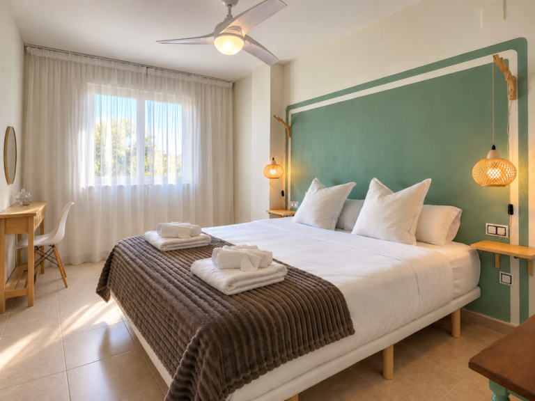 Dormitorio principal de Ático MarLuc en El Campello con cama doble, cabecero verde y luz natural