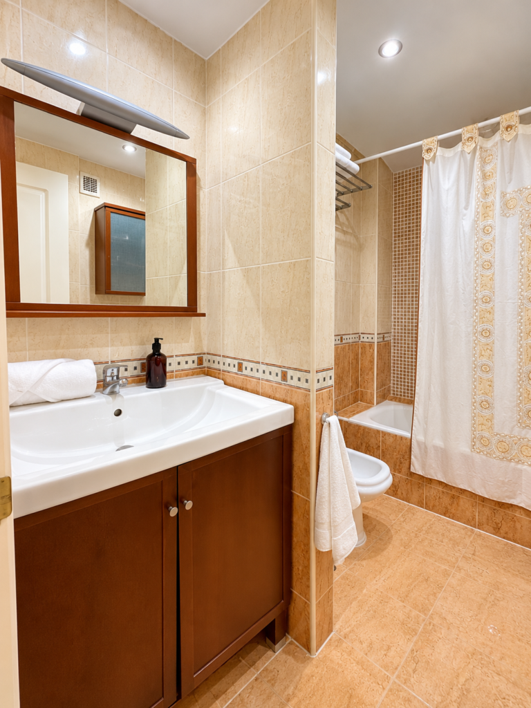 Lavabo con mueble de madera y espejo en el baño de la suite de Ático MarLuc