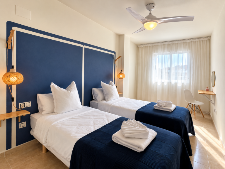 Dormitorio de dos camas individuales de Ático MarLuc en El Campello con cabecero azul