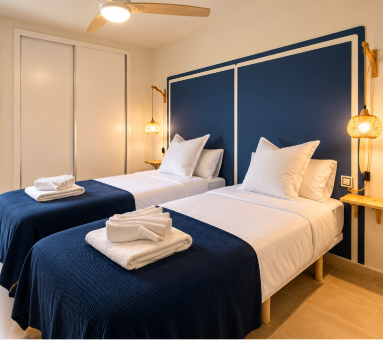 Dos camas individuales con ropa de cama azul en el segundo dormitorio de Ático MarLuc